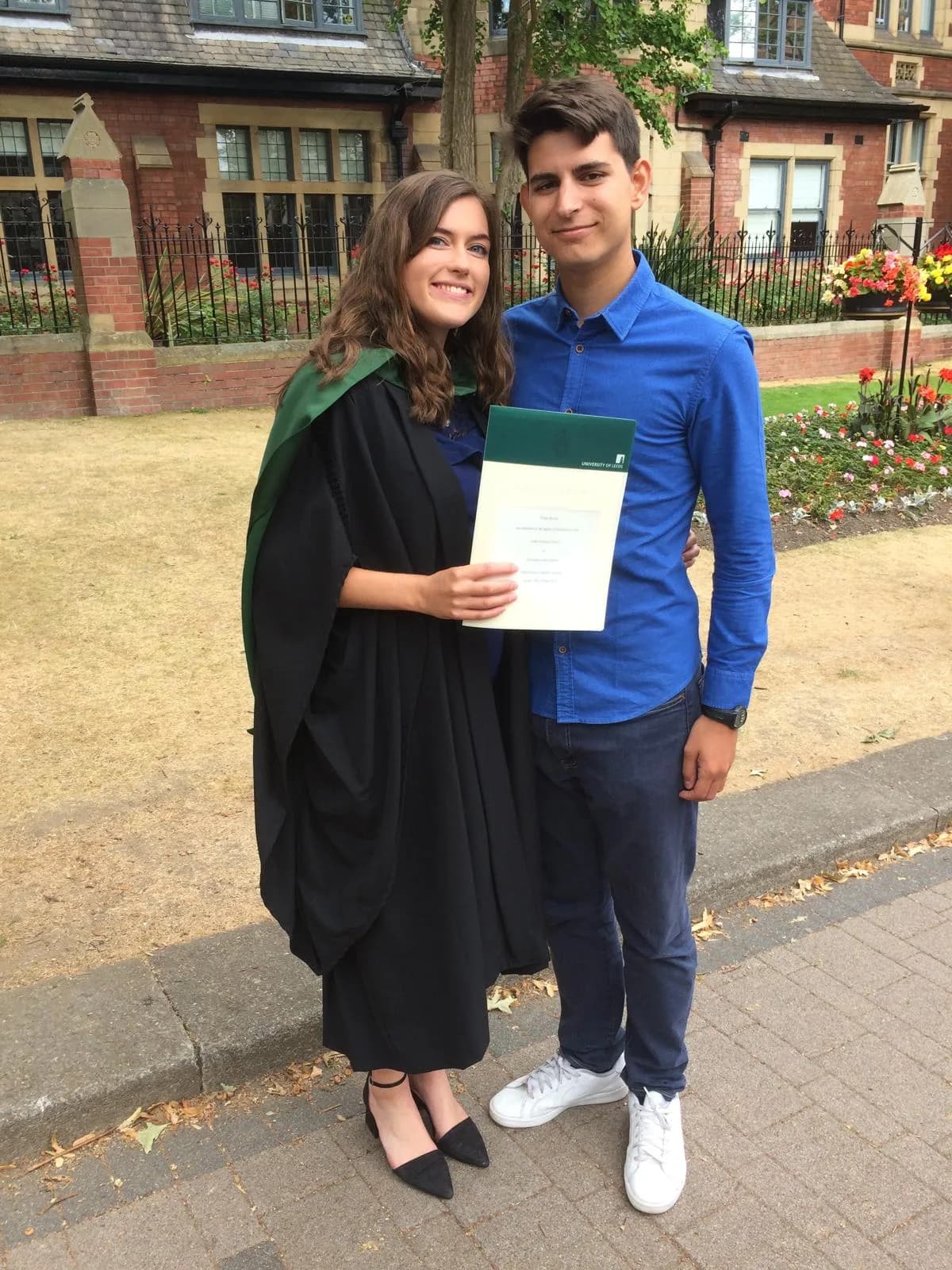 Kirsty in graduation gown holding certificate outdoors